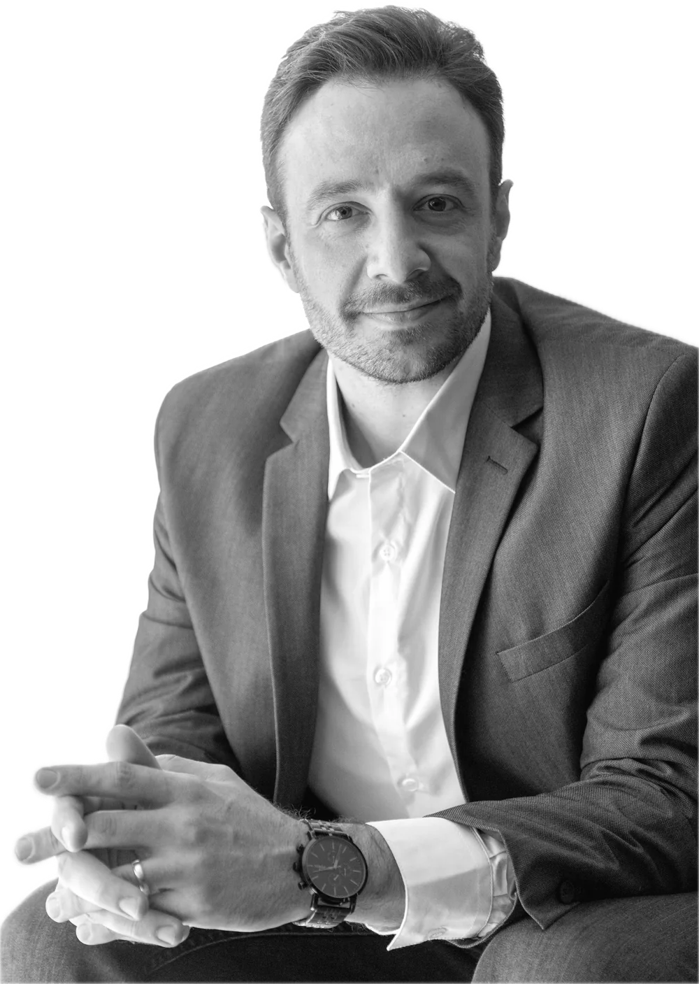 A businessman in a jacket and white shirt smiles, hands together.